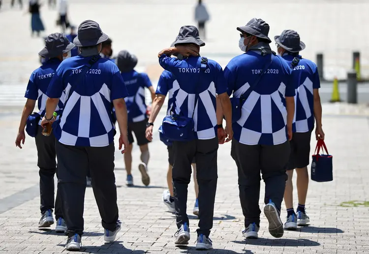 Voluntários dos Jogos de Tóquio caminham por rua da capital japonesa
 (Issei Kato/Reuters)