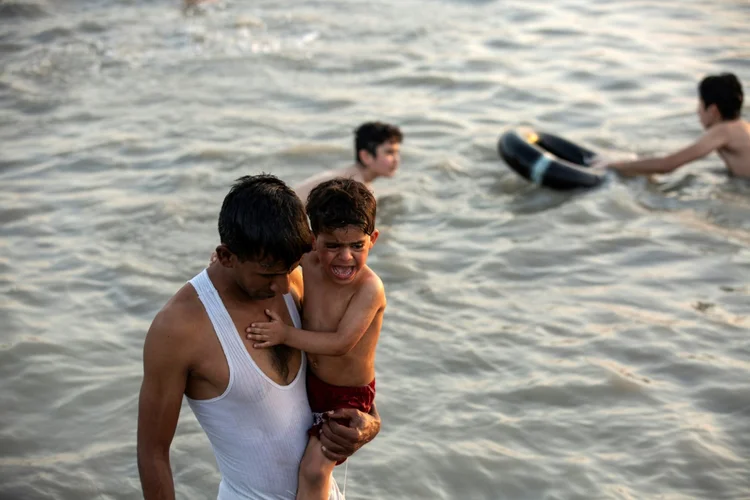 Iraquianos nadam no rio Shatt Al-Arab, em meio a uma onda de calor que atinge todo o país, que também sofre grandes cortes de energia no calor da onda de calor (AFP/AFP)