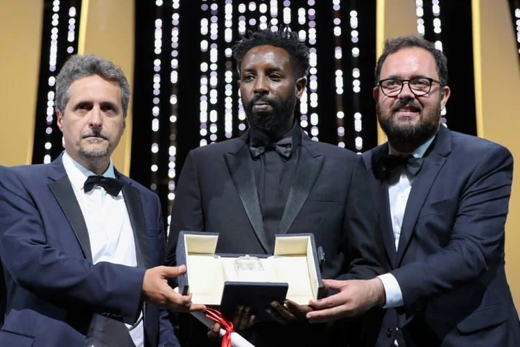 Diretor francês Ladj Ly (Centro) posa com os diretores Juliano Dornelles (Direita) e Kleber Mendonça Filho, que recebem prêmio do júri no Festival de Cannes em 25 de maio de 2019. (Anna Pelegri/AFP)