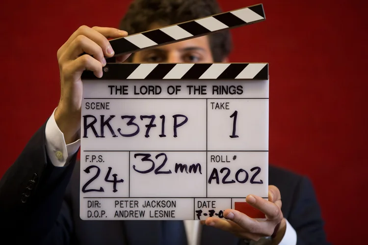 Assistente de galeria posa com claquete durante filmagem de "O Senhor dos Anéis" em casa de leilões de Londres. (Neil Hall/Reuters)