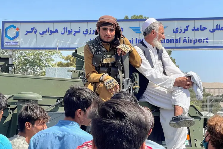 Afeganistão: combatente do Taliban senta em cima de veículo blindado do lado de fora do Aeroporto Internacional Hamid Karzai, em Cabul (Stringer/Reuters)