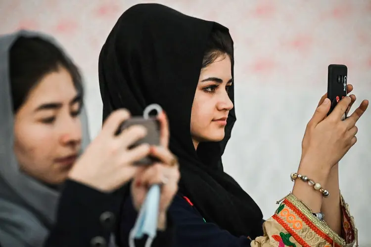 Mulheres afegãs usam celular para tirar fotos de uma reunião contra as alegadas violações dos direitos humanos contra as mulheres pelo regime do Talibã no Afeganistão, em 2 de agosto de 2021 (SAJJAD HUSSAIN/AFP/Getty Images)