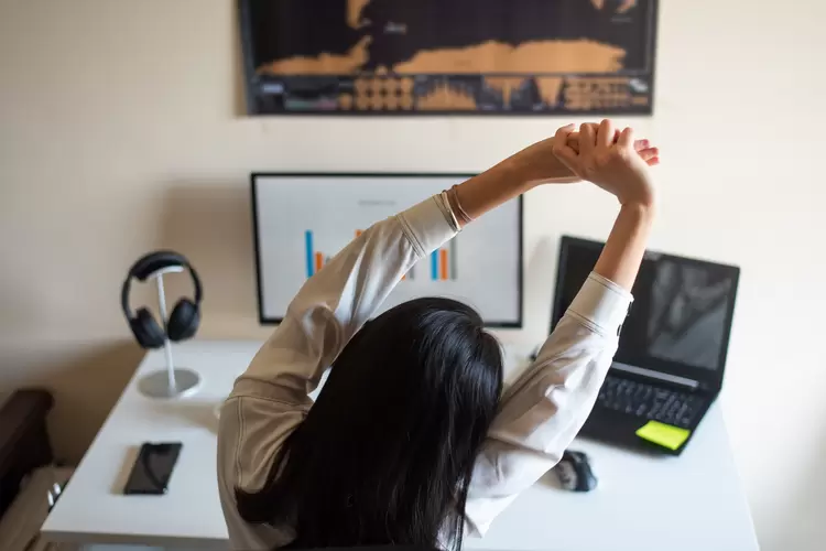 Woman stretching while working on computer from a home office (Stefan Tomic/Getty Images)