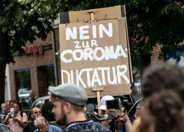 Manifestantes antirrestrições marcham em um protesto proibido em Berlim com um cartaz que diz "Não à ditadura do corona" (AFP/AFP)