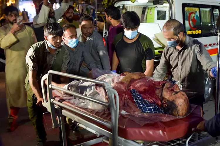 EDITORS NOTE: Graphic content / Volunteers and medical staff bring an injured man for treatment after two powerful explosions, which killed at least six people, outside the airport in Kabul on August 26, 2021. (Photo by Wakil KOHSAR / AFP) (Photo by WAKIL KOHSAR/AFP via Getty Images) (WAKIL KOHSAR/AFP via Getty Images/Getty Images)