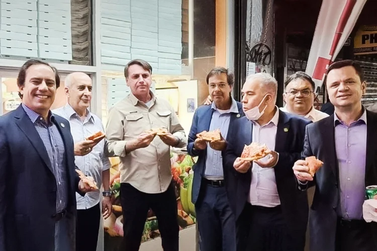 O presidente do Brasil, Jair Bolsonaro, come pizza na rua em Nova York, antes da Assembleia Geral da ONU, ao lado do presidente da Caixa, Pedro Guimarães; Luiz Eduardo Ramos, ministro-chefe da Secretaria-Geral da Presidência; Gilson Machado Neto, ministro do Turismo; e Marcelo Queiroga, ministro da Saúde; entre outros (Reprodução/Instagram)