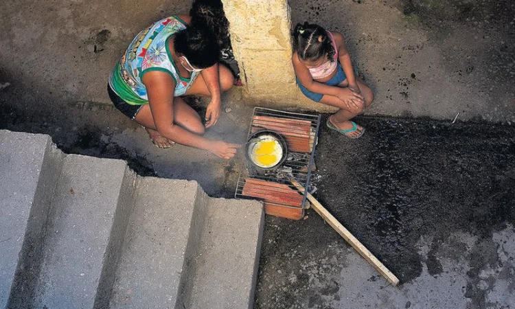 Rayane Oliveira, de 24 anos, economiza o gás, que não dá para o mês inteiro, cozinhando sobre dois tijolos com uma grade por cima (Márcia Foletto/Agência O Globo)