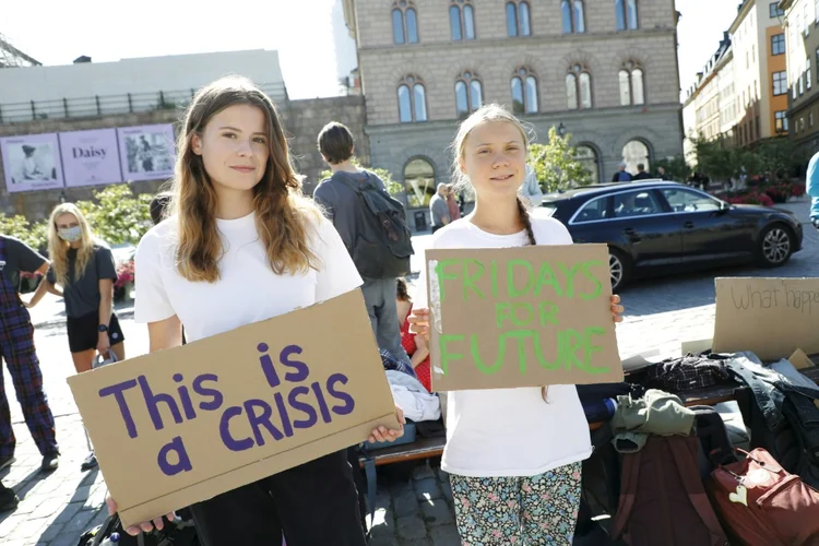 A ativista climática alemã Luisa Neubauer (E) e a ativista sueca Greta Thunberg protestam em frente ao Parlamento sueco durante uma manifestação  (AFP/AFP)