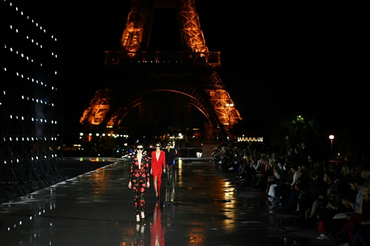 O desfile aconteceu diante de uma Torre Eiffel que piscava e ao lado de uma parede de refletores. (AFP/AFP)