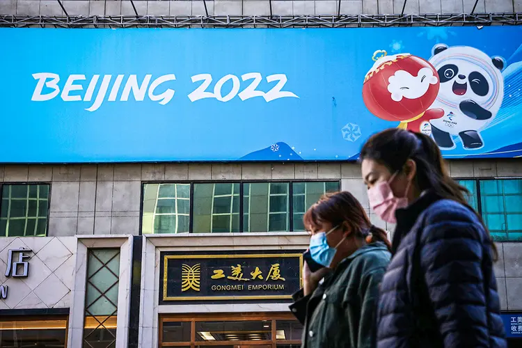Pessoas caminham próximo a cartaz com o logo da Olimpíada de Inverno Pequim 2022 em Pequim. (Tingshu Wang/Reuters)