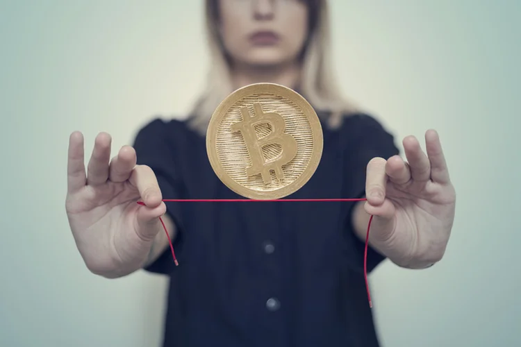 Woman's hands hold Gold Bitcoin on a thread (Francesco Carta fotografo/Getty Images)