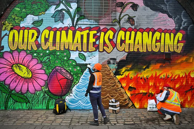 Artistas pintam um mural em uma parede próxima à via expressa Clydeside, perto do Scottish Events Centre (SEC), que sedia a Cúpula do Clima da ONU COP26 (Jeff J Mitchell/Getty Images)
