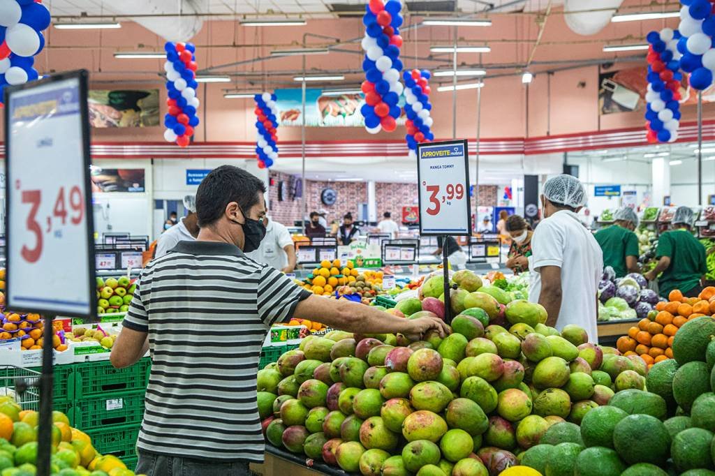 Homem seleciona laranjas em mercado: preço dos alimentos deve ajudar a derrubar inflação de setembro (Leandro Fonseca/Exame)