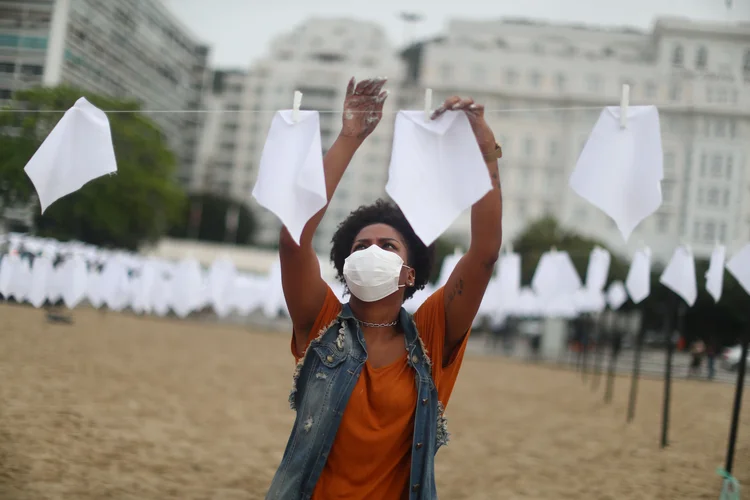 Integrante da ONG Rio de Paz prende lenços brancos na praia de Copacabana, no Rio de Janeiro, em sinal de luto e de homenagem aos 600 mil brasileiros mortos na pandemia de Covid-19 (Pilar Olivares/Reuters)