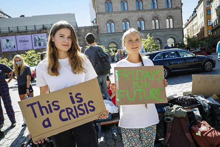 A ativista climática alemã Luisa Neubauer (E) e a ativista sueca Greta Thunberg protestam em frente ao Parlamento sueco durante uma manifestação  (AFP/AFP)