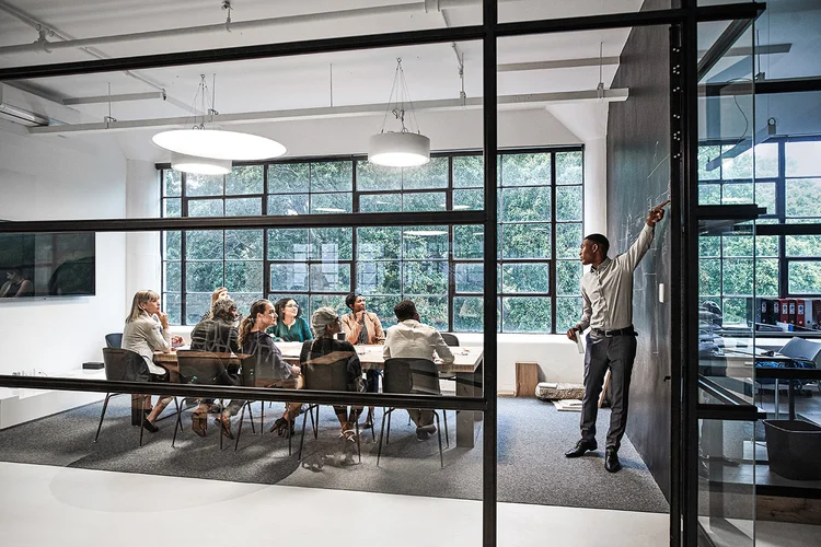 Businessman pointing and discussing while male and female colleagues sitting in board room during office meeting (Klaus Vedfelt/Getty Images)