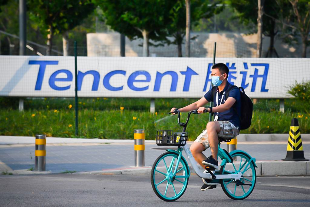 Um homem passa por uma placa da Tencent do lado de fora da sede da empresa, em Pequim (GREG BAKER/Getty Images)