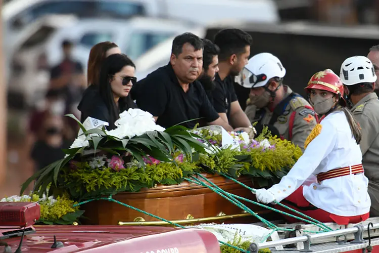 Maiara e Maraísa sentam-se em um caminhão de bombeiros ao lado do caixão da cantora brasileira Marília Mendonça (Mateus Bonomi/Getty Images)