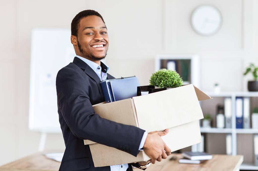 Happy black businessman moving to new office with box and his belongings, copy space. Successful african american manager holding box with working stuff, changing working place (Shutterstock/Shutterstock)