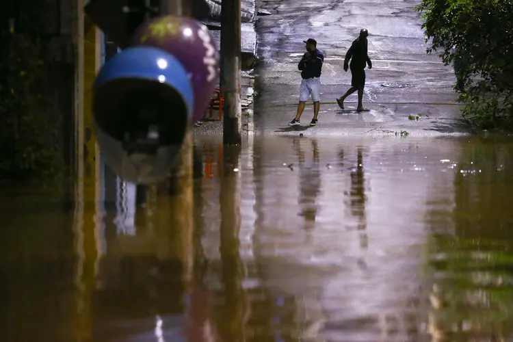 Pessoas ficam em rua inundada após forte chuva em São Paulo (Carla Carniel/Reuters)