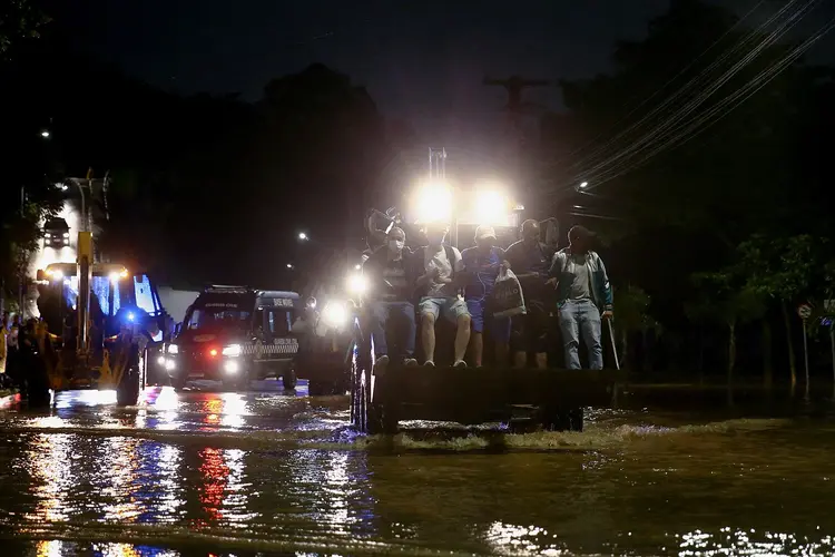 Chuvas em São Paulo: Trator transporta pessoas por uma rua alagada após fortes chuvas em Caieiras  (Carla Carniel/Reuters)