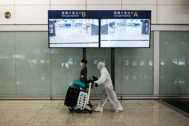 Passageiro usa equipamento de proteção, como medida de precaução contra o coronavírus COVID-19, após chegar ao aeroporto internacional de Hong Kong. (ANTHONY WALLACE/AFP/Getty Images)