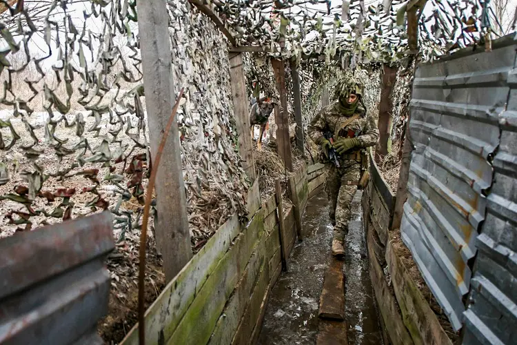 Soldado das Forças Militares da Ucrânia caminha em uma trincheira na linha de frente com separatistas apoiados pela Rússia perto de Avdiivka, Donetsk, sudeste da Ucrânia, em 9 de janeiro de 2022. (Anatolii STEPANOV/AFP)