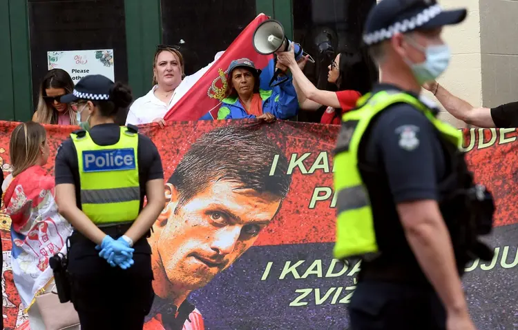 Fãs com cartazes do tenista Novak Djokovic em frente ao centro onde o atleta está retido. (AFP/AFP)