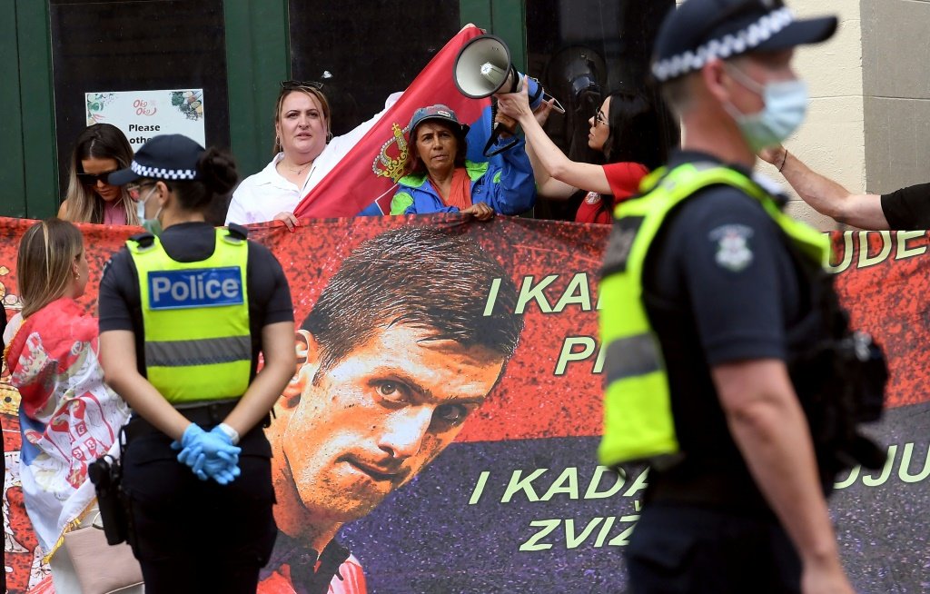 Fãs com cartazes do tenista Novak Djokovic em frente ao centro onde o atleta está retido, em Melbourne, na Austrália, após ter o visto negado por não ter sido vacinado contra a covid-19 (AFP/AFP)