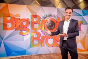 Tadeu Schmidt em frente ao logo do Big Brother Brasil
