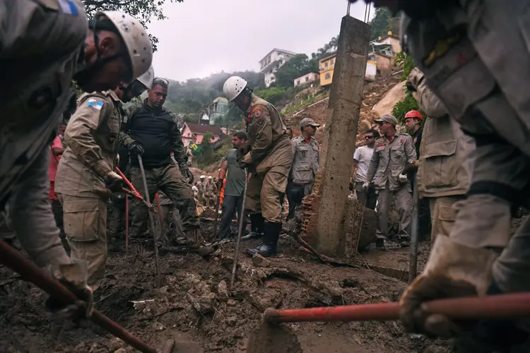 Bombeiros são vistos durante missão de resgate após deslizamento de terra gigante no bairro de Caxambu, em Petrópolis, Brasil, em 19 de fevereiro de 2022. (MAURO PIMENTEL/AFP)