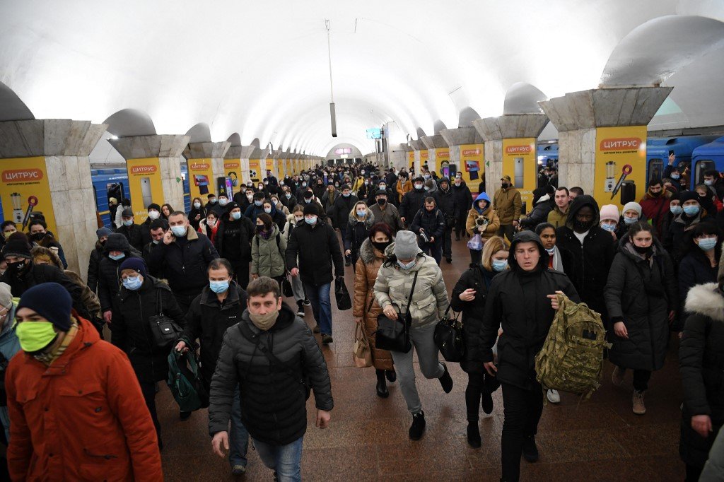 Pessoas, algumas carregando bolsas e malas, caminham em uma estação de metrô em Kiev no início de 24 de fevereiro de 2022.