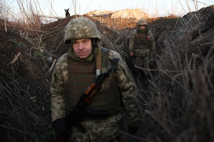 Militares das Forças Militares Ucranianas caminham ao longo de tranches em sua posição na linha de frente com separatistas apoiados pela Rússia, perto da vila de Novognativka, região de Donetsk, em 21 de fevereiro de 2022 (Anatolii STEPANOV/AFP)