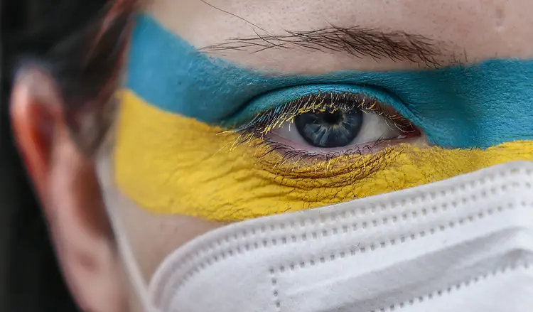 Mulher usa maquiagem nas cores da bandeira ucraniana protestando contra a invasão russa da Ucrânia. (Hannibal Hanschke/Getty Images)