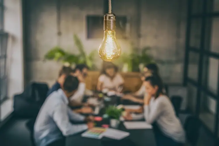 Young business people are discussing together a new startup project. A glowing light bulb as a new idea. (scyther5/Getty Images)