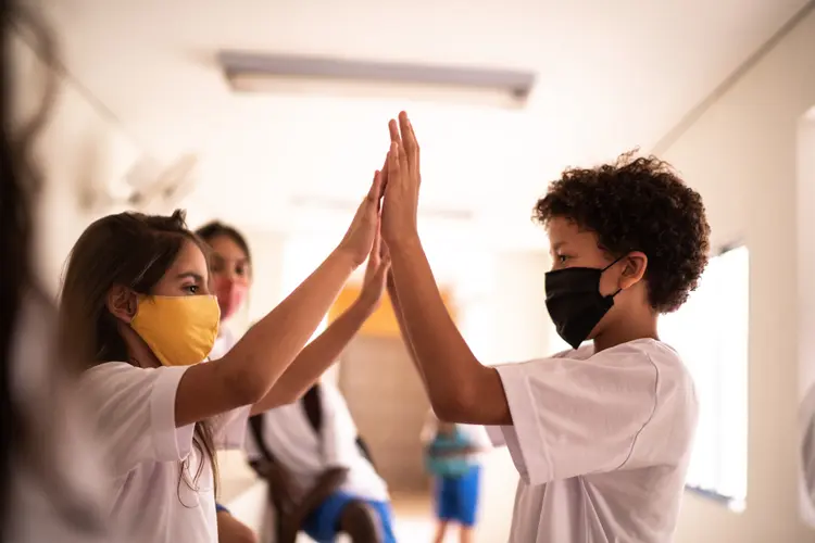 Friends playing clapping game during school's break time using face mask (Royalty-free/Getty Images)