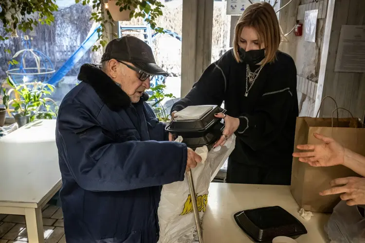 Funcionário do restaurante Chernomorka distribui almoços grátis para moradores, em Kiev. (FADEL SENNA/AFP)