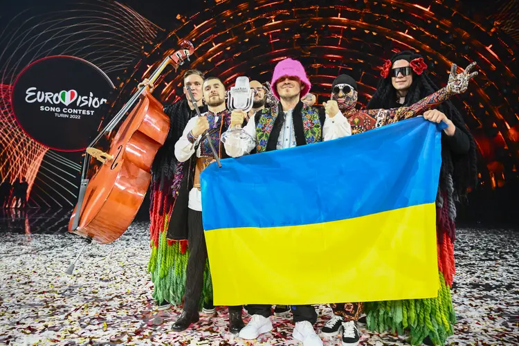 Membros do 'Kalush Orchestra' posam no palco com o troféu de vencedor e a bandeira da Ucrânia depois de vencerem em nome do país o Festival Eurovision em 14 de maio de 2022, na Itália (Marco BERTORELLO/AFP)