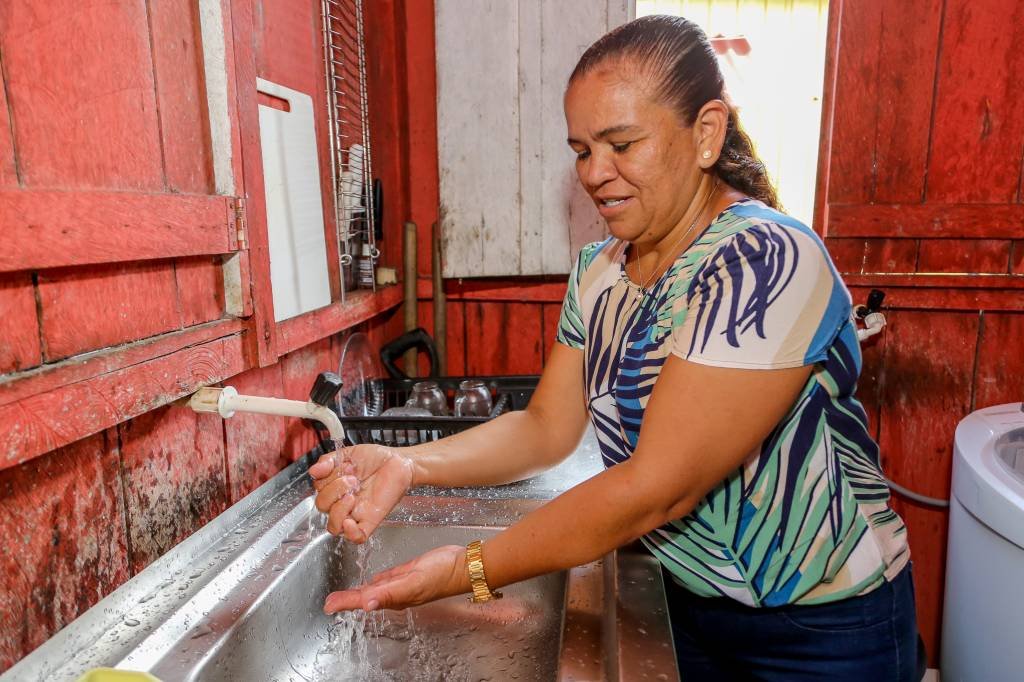 Gisele Dantas, moradora de Cachoeirinha, em Manaus, mostra água tratada implantada no bairro