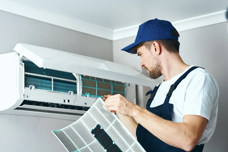 A hired worker repairman cleans and repairs the air conditioner. (ShotPrime/Getty Images)