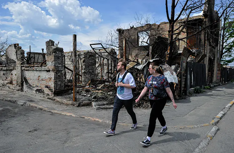 IRPIN, UKRAINE - 2022/05/08: People walk past a house destroyed by Russian shelling in the city of Irpin, near the Ukrainian capital Kyiv. Russia invaded Ukraine on 24 February 2022, triggering the largest military attack in Europe since World War II. (Photo by Sergei Chuzavkov/SOPA Images/LightRocket via Getty Images) (Sergei Chuzavkov/SOPA Images/LightRocket via Getty Images/Getty Images)