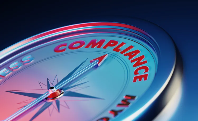 The arrow of the compass is pointing the compliance word over dark blue metallic background. Horizontal composition with copy space. Compliance concept. (MicroStockHub/Getty Images)