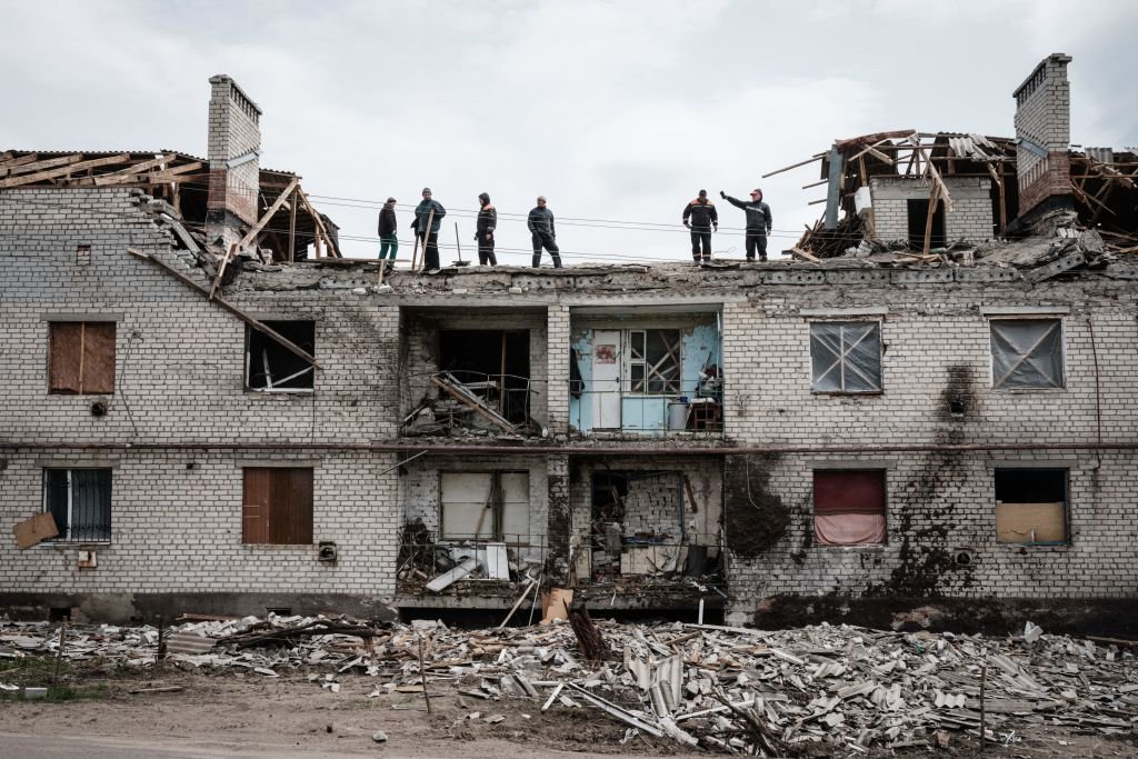 Trabalhadores limpam escombros em cima de um prédio destruído por bombardeios há um mês em Cherkaske, leste da Ucrânia, em 11 de maio de 2022, em meio à invasão russa da Ucrânia