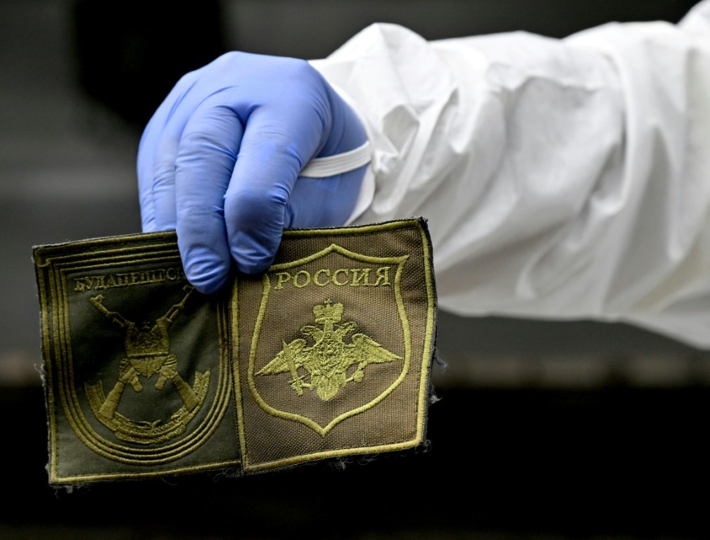 Legista ucraniano mostra as insígnias encontradas no uniforme de um soldado russo morto em Zavlivka, oeste de Kiev: milhares de russos mortos (AFP/AFP)