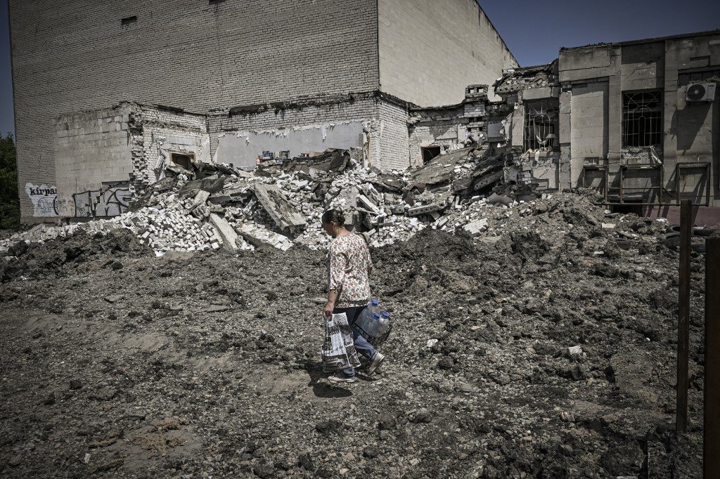 Uma mulher caminha em frente a um prédio destruído por um ataque na cidade de Lysytsansk, na região leste ucraniana de Donbas, em 30 de maio de 2022, no 96º dia da invasão russa da Ucrânia.