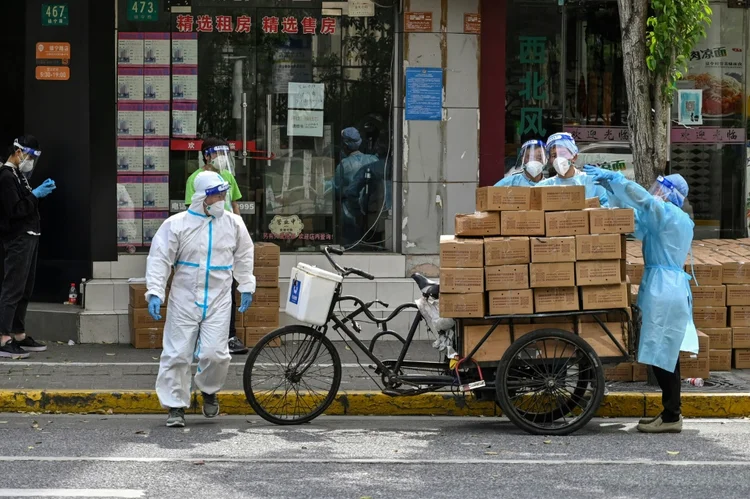 Trabalhadores com trajes de proteção separam caixas, cujo conteúdo será distribuído em Xangai, China, em 18 de maio de 2022. (AFP/AFP)