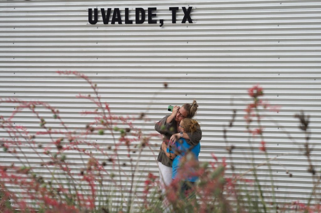 Mulher chora e abraça uma menina em frente ao Centro Cívico Willie de Leon, em Uvalde, Texas, após o tiroteio na escola primária da cidade