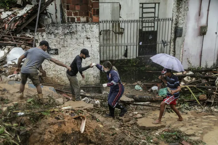 Moradores e equipes de resgate caminhando em meio aos escombros de um deslizamento de terra que destruiu várias casas na comunidade Jardim Monte Verde, bairro do Ibura, em Recife (Divulgação/Prefeitura de Recife via/AFP)