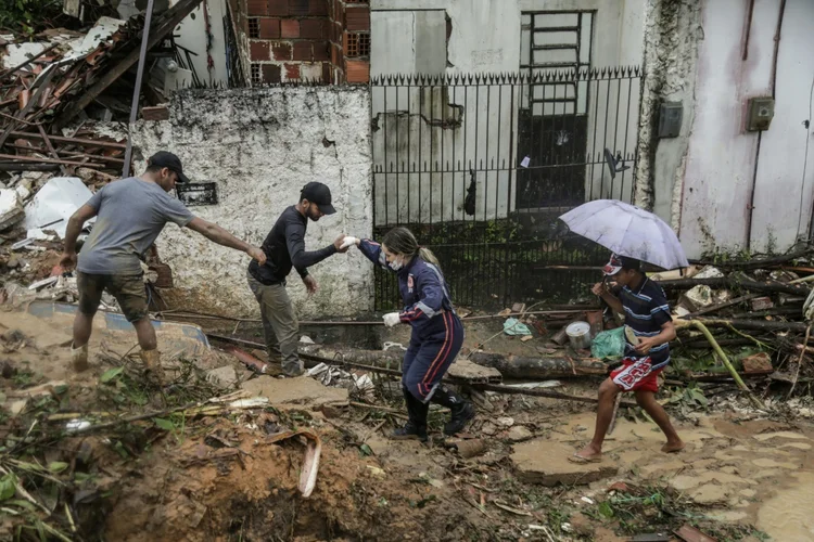 Moradores e equipes de resgate caminhando em meio aos escombros de um deslizamento de terra que destruiu várias casas na comunidade Jardim Monte Verde, bairro do Ibura, em Recife (Divulgação/Prefeitura de Recife via/AFP)