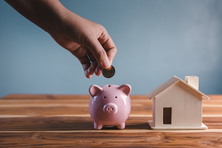Money Savings for Future Property House Concept, Hand is Putting Coin Into Piggy Bank for Saving Future Housing Real Estate Ownership. Banking Fund for Investing House Asset and Real Estate (Getty/Getty Images)